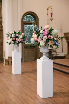 three white vases with flowers in them sitting on top of a wooden floor next to each other