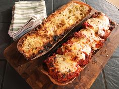 two slices of bread with sauce and cheese on them sitting on a wooden cutting board