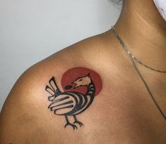 a bird tattoo on the back of a woman's upper arm, with a red circle in the background