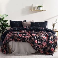 a bed with black and pink floral comforter set on top of white fluffy carpet