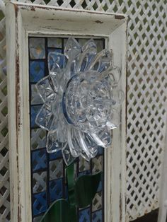 a glass flower is placed in front of a stained glass wall hanging on a chain link fence