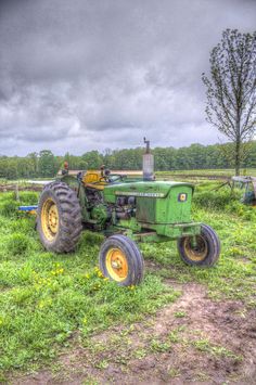 an old green tractor sitting in the middle of a field