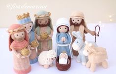 crocheted nativity figurines are displayed on a white surface with christmas lights in the background