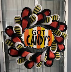 a wreath that says got candy on it with red, black and yellow ribbons around it