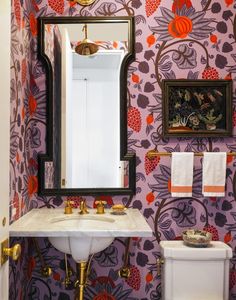 the bathroom is decorated in pink and purple with gold accents on the walls, along with an ornate mirror above the sink