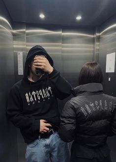 two people standing in front of a mirror with their backs turned to the same direction