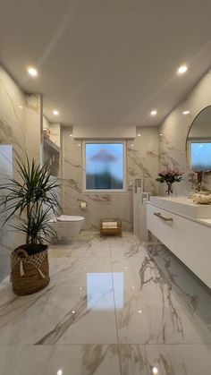 a large bathroom with marble floors and white walls, along with a plant in the corner