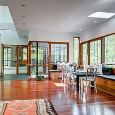 a living room filled with lots of furniture next to large windows and wooden flooring