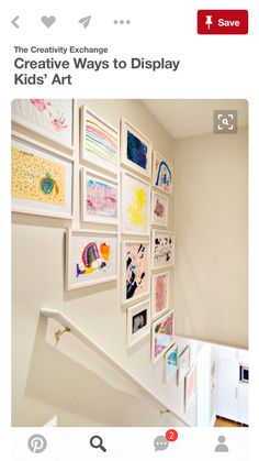 there are many framed pictures on the wall next to the stair case in this house