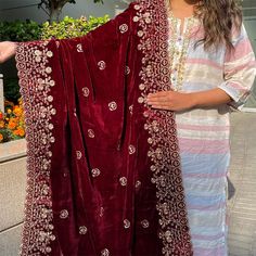 a woman holding up a red velvet shawl