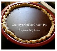 a chocolate cream pie sitting on top of a red plate with the words granny's cocoa cream pie forgotten way farms