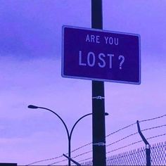 a purple sign that says are you lost? on the side of a fenced in area