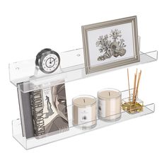 a shelf with candles, pictures and other items on it that include an alarm clock