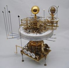 a clock with many different parts attached to it's sides, including the dials and pendulums