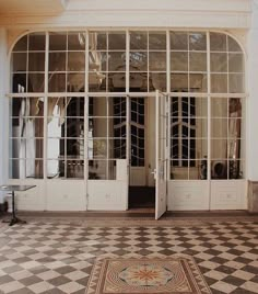 an entrance to a large white building with glass doors and railings on the second floor