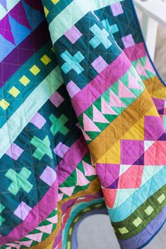 a multicolored quilt sitting on top of a white chair