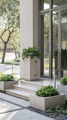 two planters with plants on the steps in front of a building's entrance