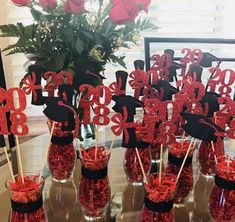 there are many red candy in vases on the table and one is decorated with black letters