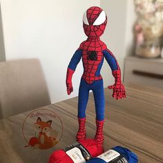 a crocheted spiderman doll sitting on top of two balls of yarn next to each other