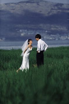 a bride and groom standing in the middle of a field