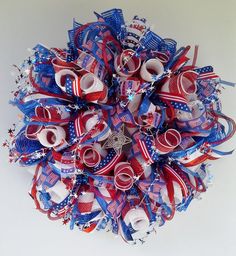 a red, white and blue wreath made out of ribbons with scissors on it's side