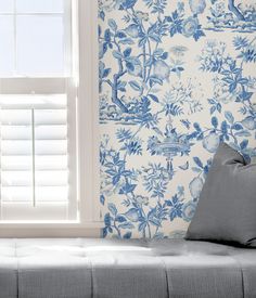 a blue and white floral wallpaper with birds on it, next to a window