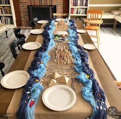 a long table is decorated with blue streamers and white plates on top of it