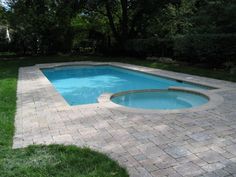 an empty swimming pool in the middle of a yard with grass and trees around it