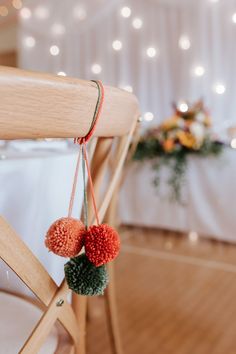 two pom - poms hanging from the back of a chair at a wedding