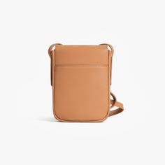 a tan leather cross body bag on a white background, with the strap hanging down