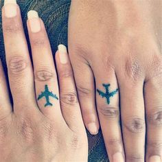 two people with tattoos on their fingers and one has an airplane tattoo on the middle finger