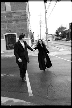 black and white photograph of two people walking down the street holding hands with each other