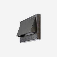 a black square light fixture on a white wall with a gray shade covering it's face