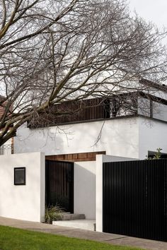 a white house with black gate and trees