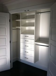 an empty closet with white doors and drawers