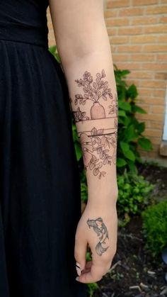 a person with a tattoo on their arm holding a flower pot and an apple tree