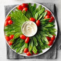 a white plate topped with spinach and tomatoes next to a bowl of mayonnaise