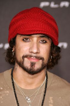 a close up of a person wearing a red hat and beads on his necklaces