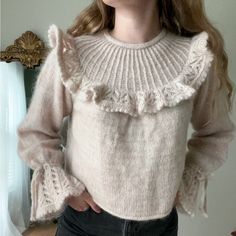 a woman wearing a sweater with ruffles on it