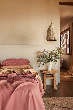 a bed sitting in a bedroom next to a wooden table and window covered with curtains