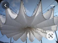 an upside down photo of some white fabric hanging from power lines with the sky in the background