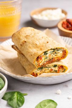 two burritos cut in half on a plate with other food items around them