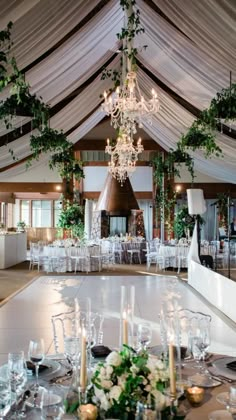 a large banquet hall with tables, chairs and chandeliers set up for an event