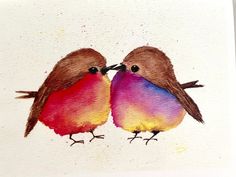 two birds sitting next to each other on top of a piece of paper with watercolor paint