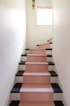 a set of black and white stairs with pink carpet