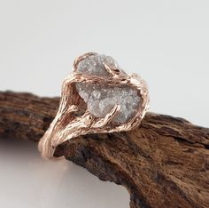 a close up of a ring on top of a piece of driftwood with white stones