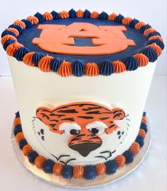 a tiger cake with the number four on it's face is decorated in blue, orange and white icing