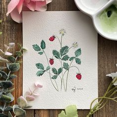 a card with flowers and berries on it sitting next to some watercolor paint pots