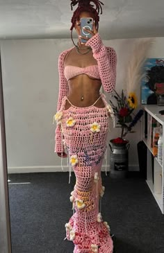 a woman in pink crocheted clothing taking a selfie