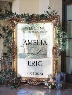 a welcome sign is displayed in front of a gold frame with greenery on it